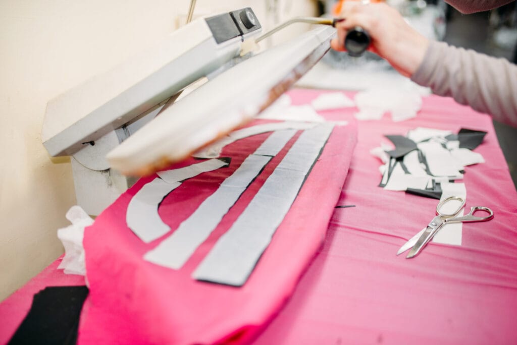 Heat press machine transferring custom garment labels at Jammy Threads workshop.