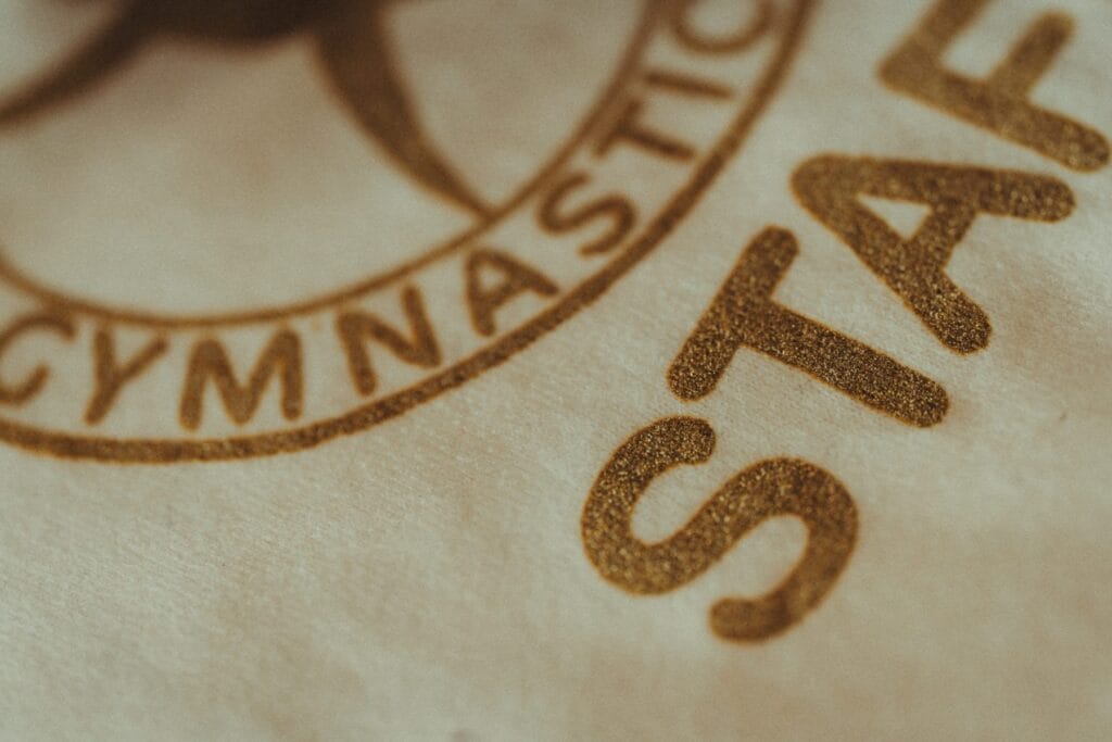 Close-up of custom printed text reading GYMNASTIC STAFF on Jammy Threads garment.